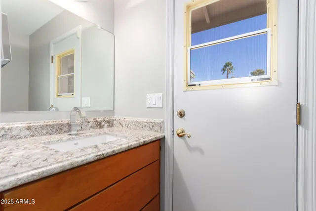 a bathroom with a granite countertop sink and a mirror