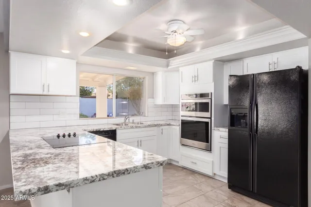 a kitchen with stainless steel appliances granite countertop a refrigerator a stove and white cabinets with wooden floor