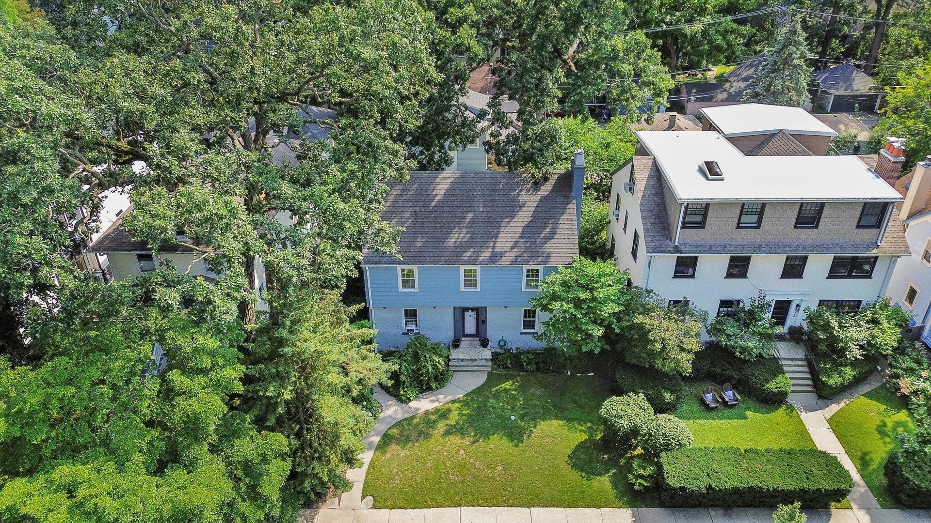 a view of a white house next to a yard with plants