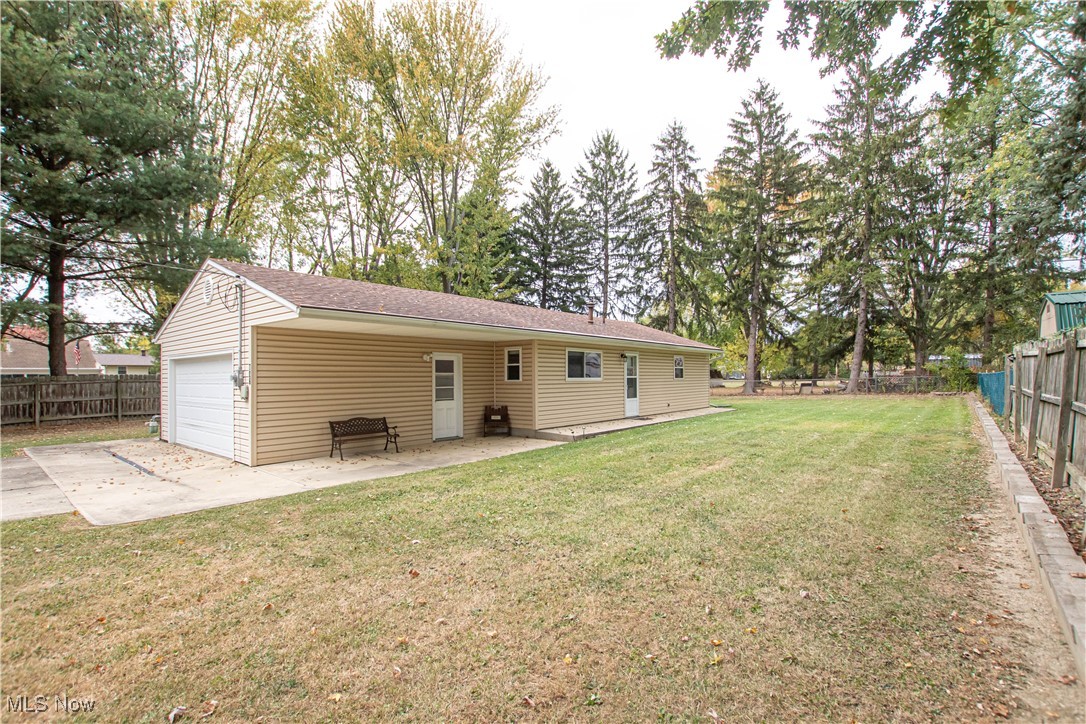 706 Abbe Road South Elyria, OH 44035 - Photo 2 of 34 Rear view of house with a fenced backyard, a patio area, concrete driveway, a shingled roof, and an attached garage