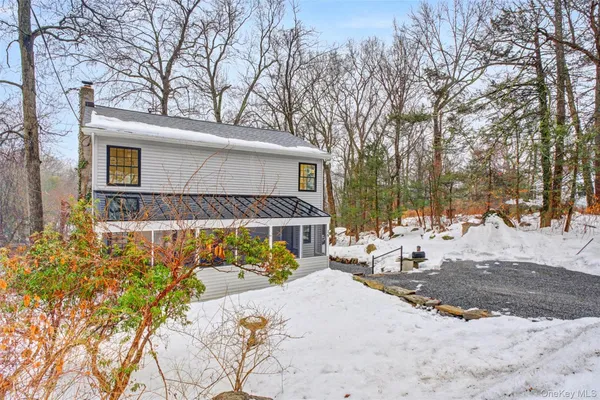 a front view of a house with a yard covered with snow and trees
