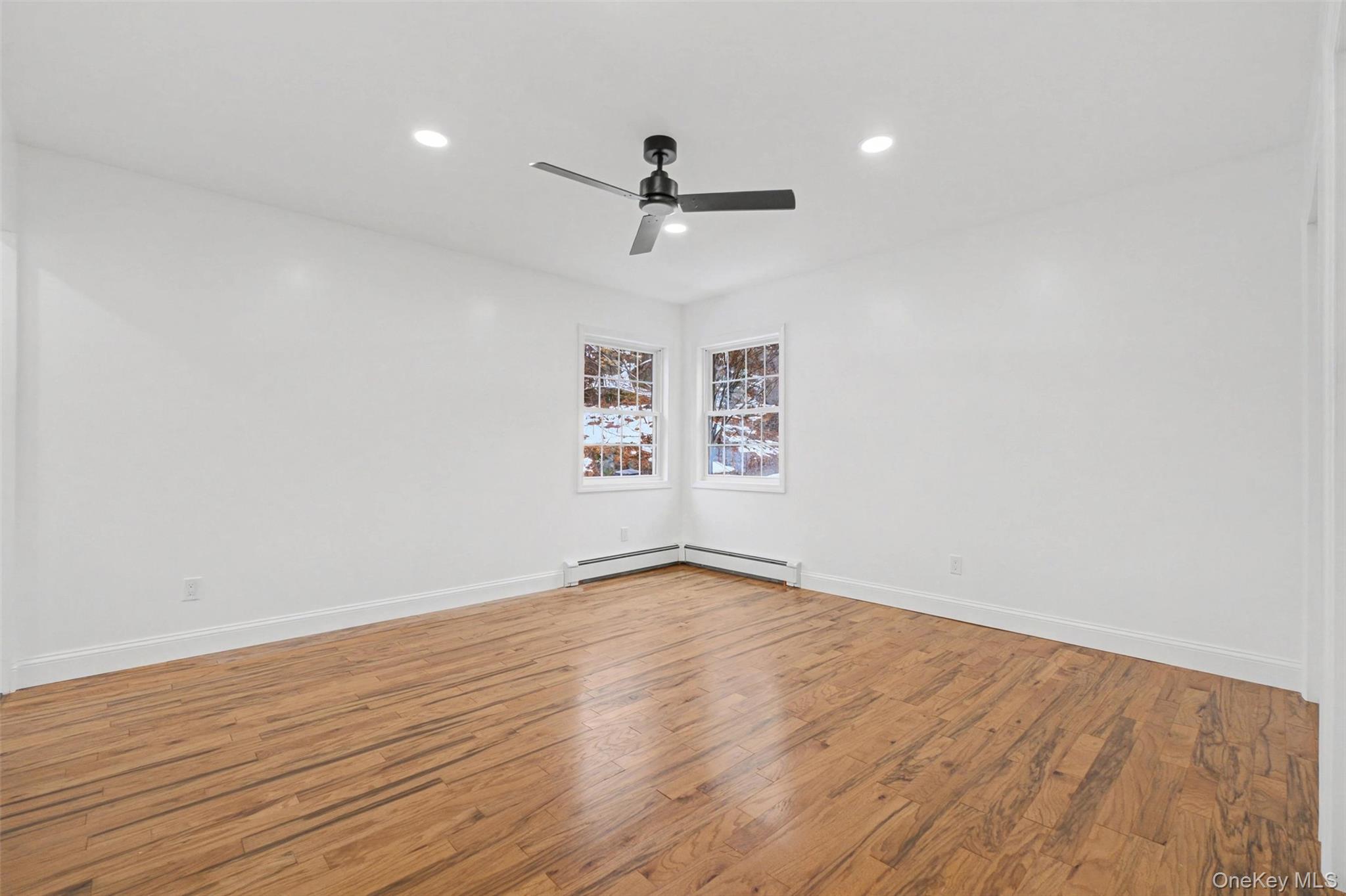 16 Cold Spring Road Putnam Valley, NY 10579 - Photo 23 of 44 an empty room with wooden floor ceiling fan and windows