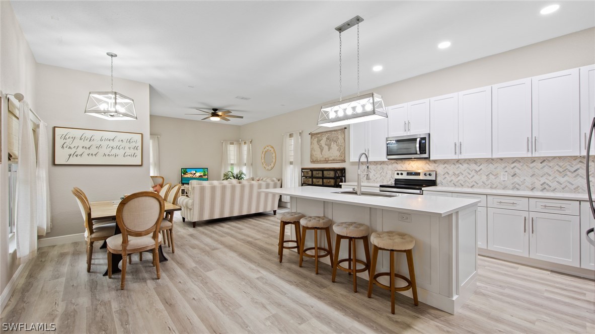 a kitchen with stainless steel appliances a dining table chairs refrigerator sink and microwave