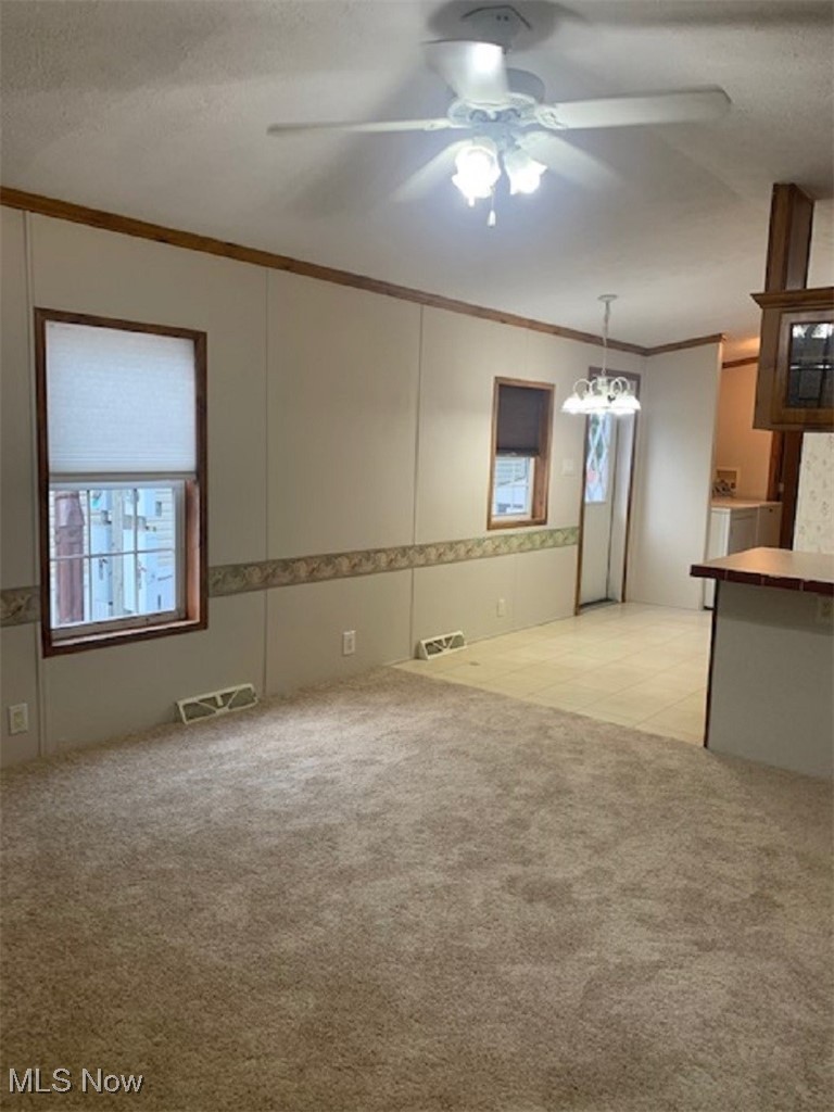 27216 Cook Road, Unit 24 Olmsted Falls, OH 44138 - Photo 3 of 23 Unfurnished room with crown molding, ceiling fan with notable chandelier, and light colored carpet