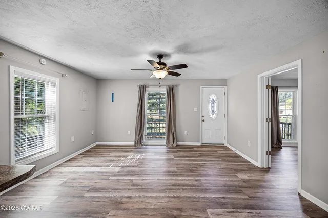 a view of an empty room with wooden floor and a window