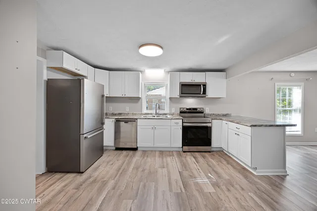 a kitchen with granite countertop a refrigerator stove top oven and sink