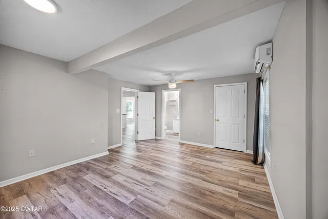 a view of an empty room with wooden floor and a window