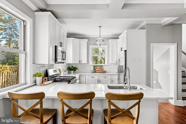 a kitchen with a dining table chairs and large windows