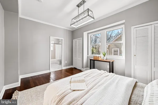 a bedroom with a bed and a large window with wooden floor