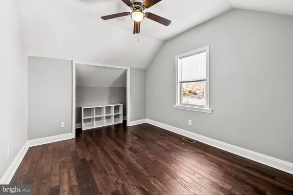 an empty room with wooden floor chandelier fan and windows