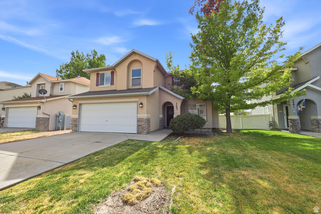 5485 Heather Way Tooele, UT 84074 - Photo 8 of 41 Two-story residence featuring a tan stucco exterior with stone accents and a red-shuttered window