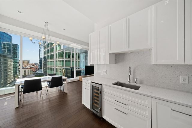 a kitchen with stainless steel appliances white cabinets a stove a sink and a potted plant