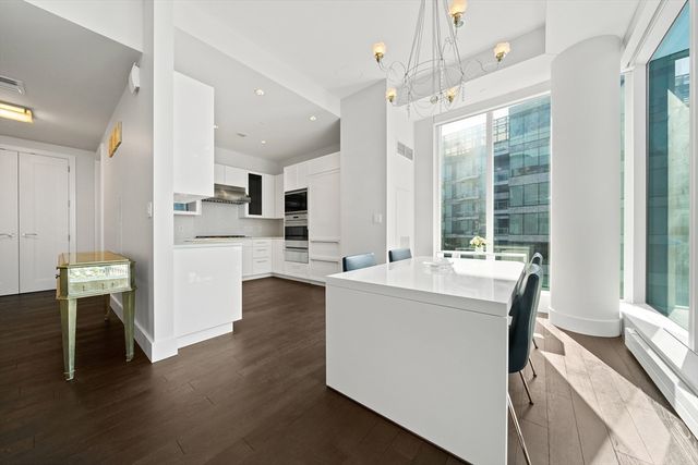 a kitchen with kitchen island a stove a refrigerator and a dining table with wooden floor