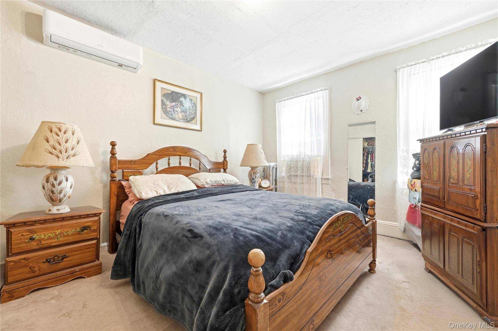 89-18 239th Street Queens, NY 11426 - Photo 9 of 14 a bedroom with a bed and flat tv screen on the dresser