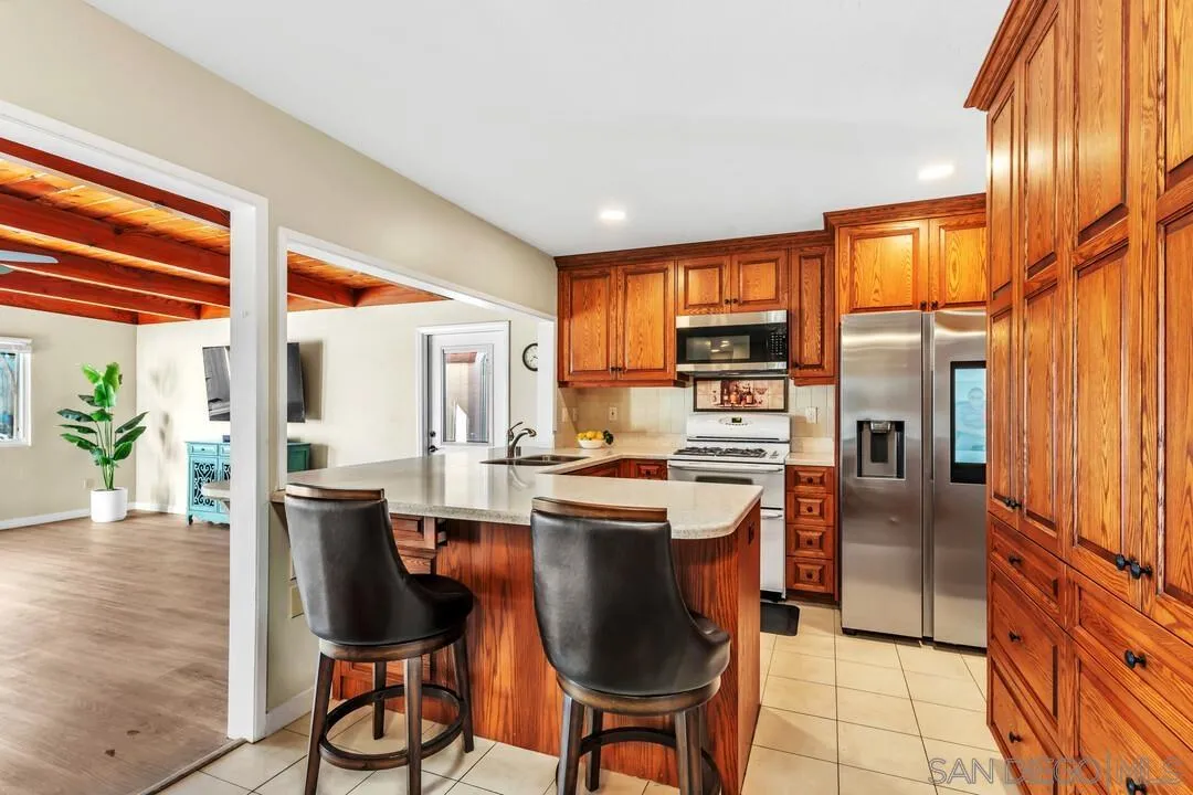 10143 Maple Tree Road Santee, CA 92071 - Photo 9 of 43 a kitchen with stainless steel appliances granite countertop a stove a refrigerator a sink dishwasher and wooden cabinets with wooden floor