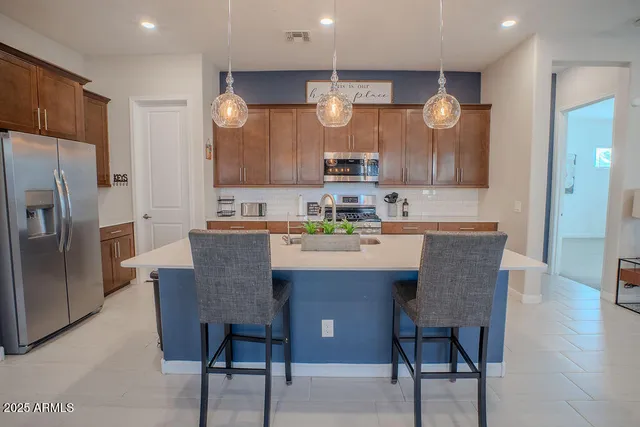 a kitchen with a dining table chairs cabinets and stainless steel appliances