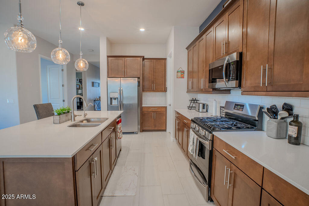 16979 West Alameda Road Surprise, AZ 85387 - Photo 7 of 33 a kitchen with stainless steel appliances granite countertop a sink a stove and a refrigerator