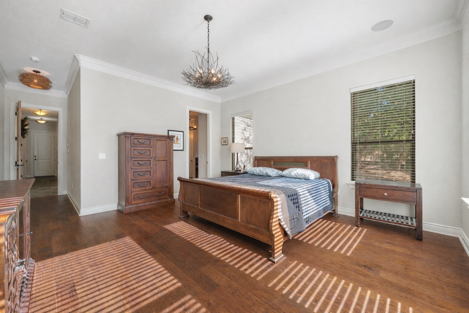 20607 Thurman Bend Road Spicewood, TX 78669 - Photo 14 of 39 a spacious bedroom with a bed and a chandelier