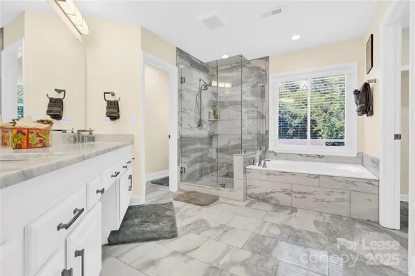 a bathroom with a granite countertop sink a mirror a bathtub and next to a window