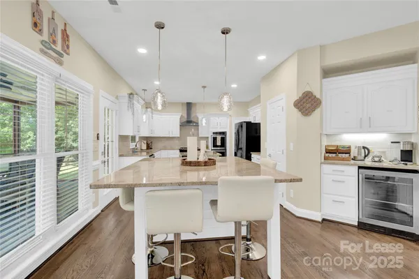 a large white kitchen with lots of counter space dining table and stainless steel appliances