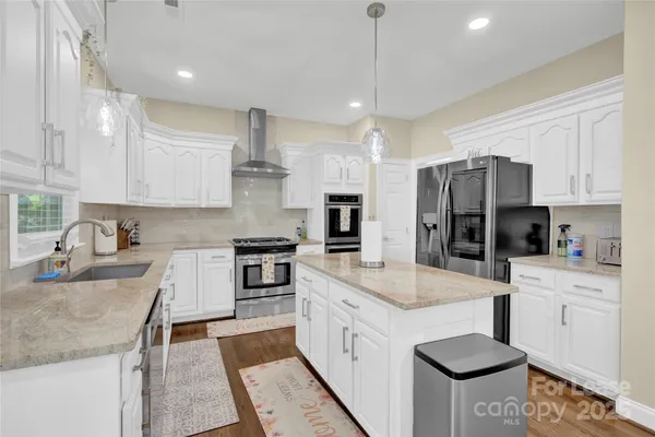 a kitchen with stainless steel appliances granite countertop a sink stove and refrigerator