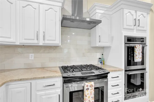 a kitchen with granite countertop a stove and a white cabinet