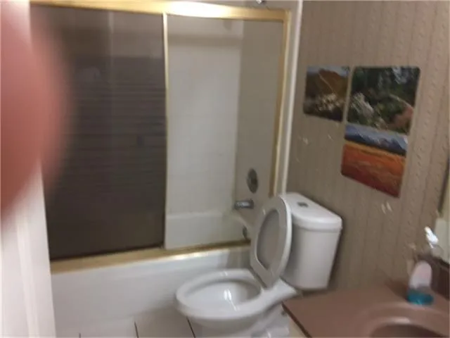 a white toilet sitting next to a bathroom sink and a mirror
