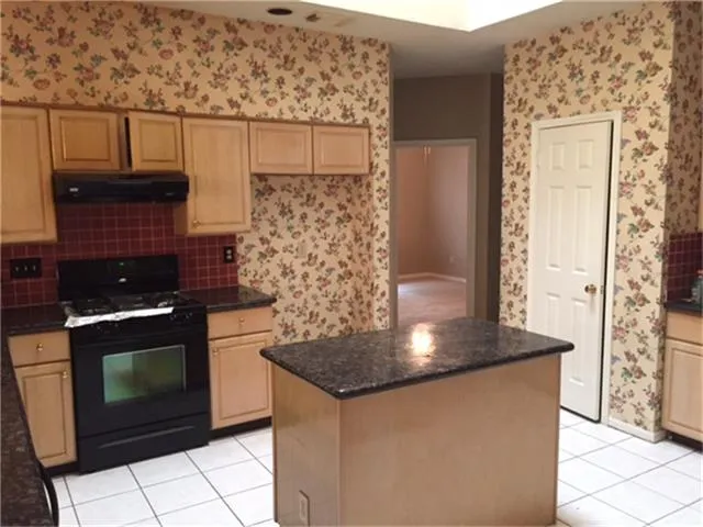 a kitchen with granite countertop a stove and a sink