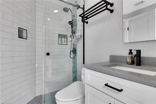 a bathroom with a granite countertop sink a toilet and shower