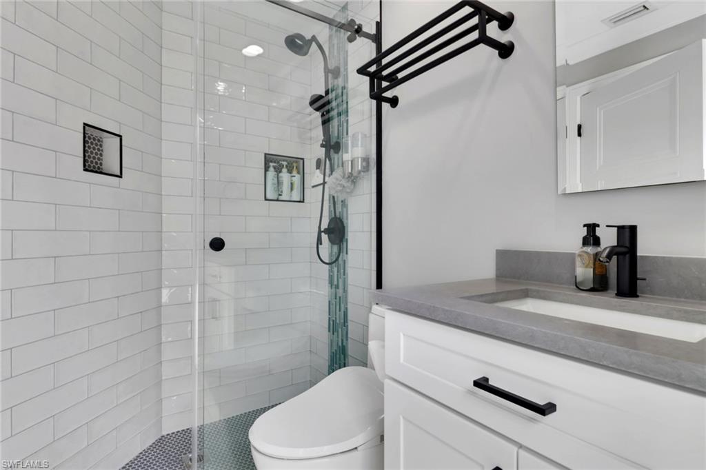 1806 Princess Court Naples, FL 34110 - Photo 31 of 40 a bathroom with a granite countertop sink a toilet and shower