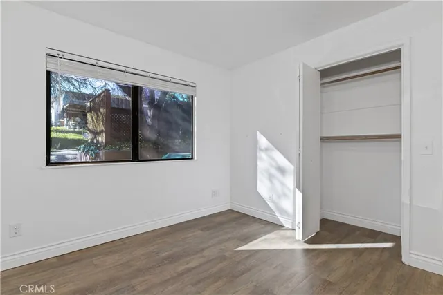 a view of an empty room with wooden floor and closet