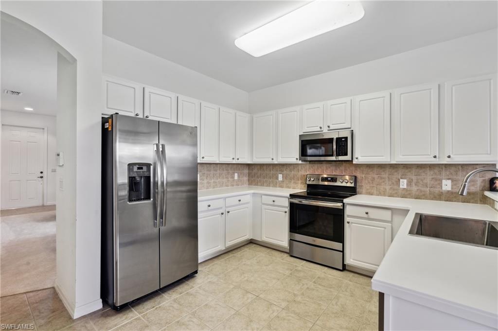 20048 Heatherstone Way, Unit 1 Estero, FL 33928 - Photo 3 of 20 a kitchen with white cabinets and stainless steel appliances
