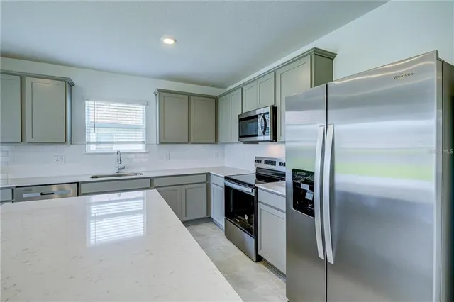 a kitchen with kitchen island a counter top space appliances and a sink