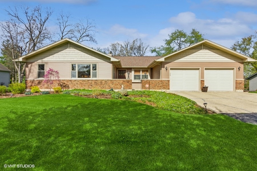 907 Powers Road Woodstock, IL 60098 - Photo 1 of 21 a front view of a house with a yard and trees