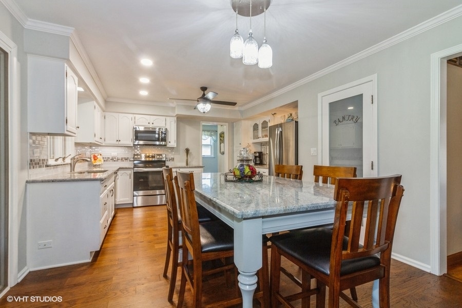 907 Powers Road Woodstock, IL 60098 - Photo 8 of 21 a kitchen with stainless steel appliances granite countertop a dining table chairs stove refrigerator and microwave