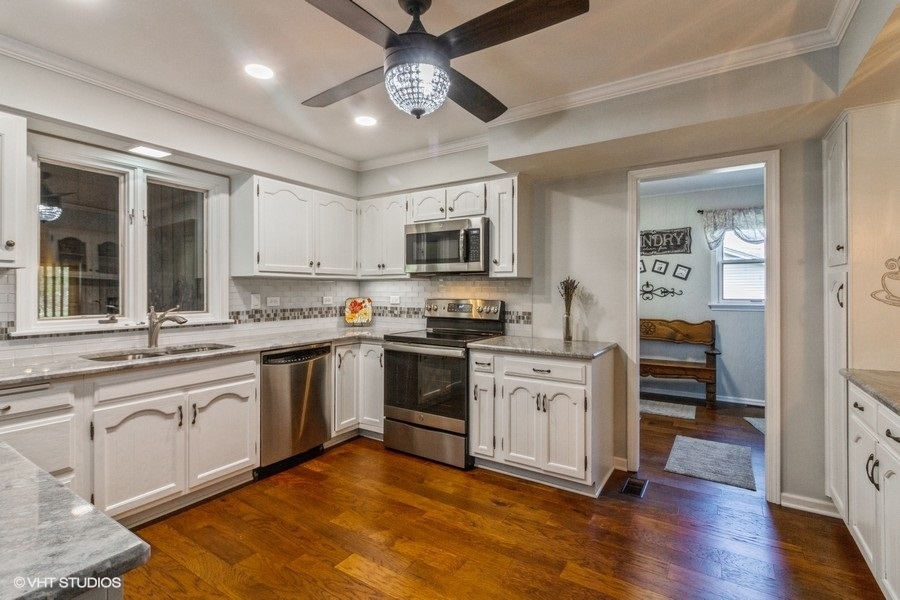 907 Powers Road Woodstock, IL 60098 - Photo 9 of 21 a kitchen with stainless steel appliances granite countertop a stove top oven a sink and white cabinets