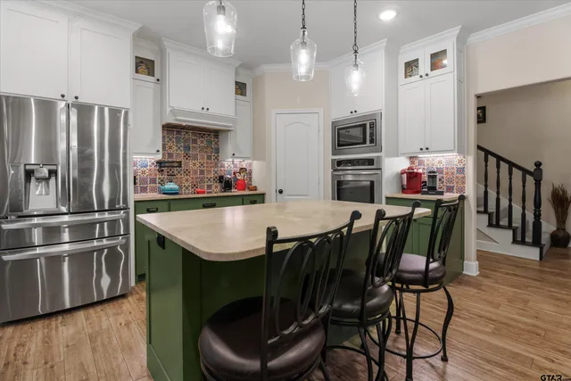 a kitchen with stainless steel appliances kitchen island granite countertop a table chairs microwave and refrigerator