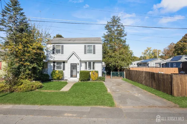 a front view of a house with a garden and trees