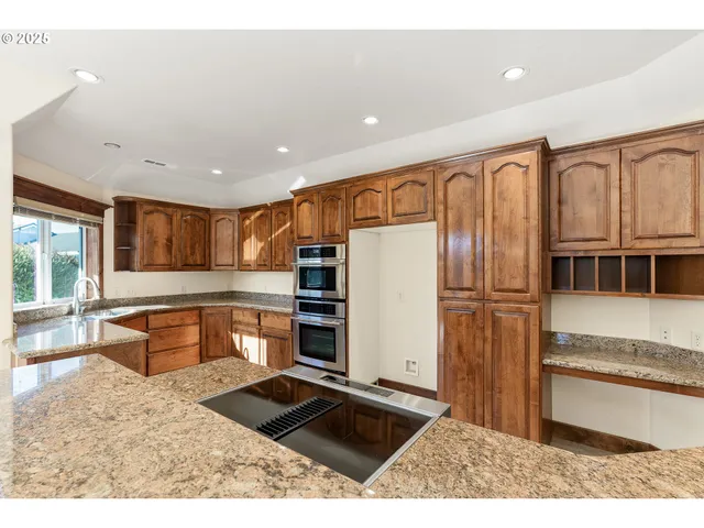 a kitchen with stainless steel appliances kitchen island granite countertop a refrigerator and a stove top oven