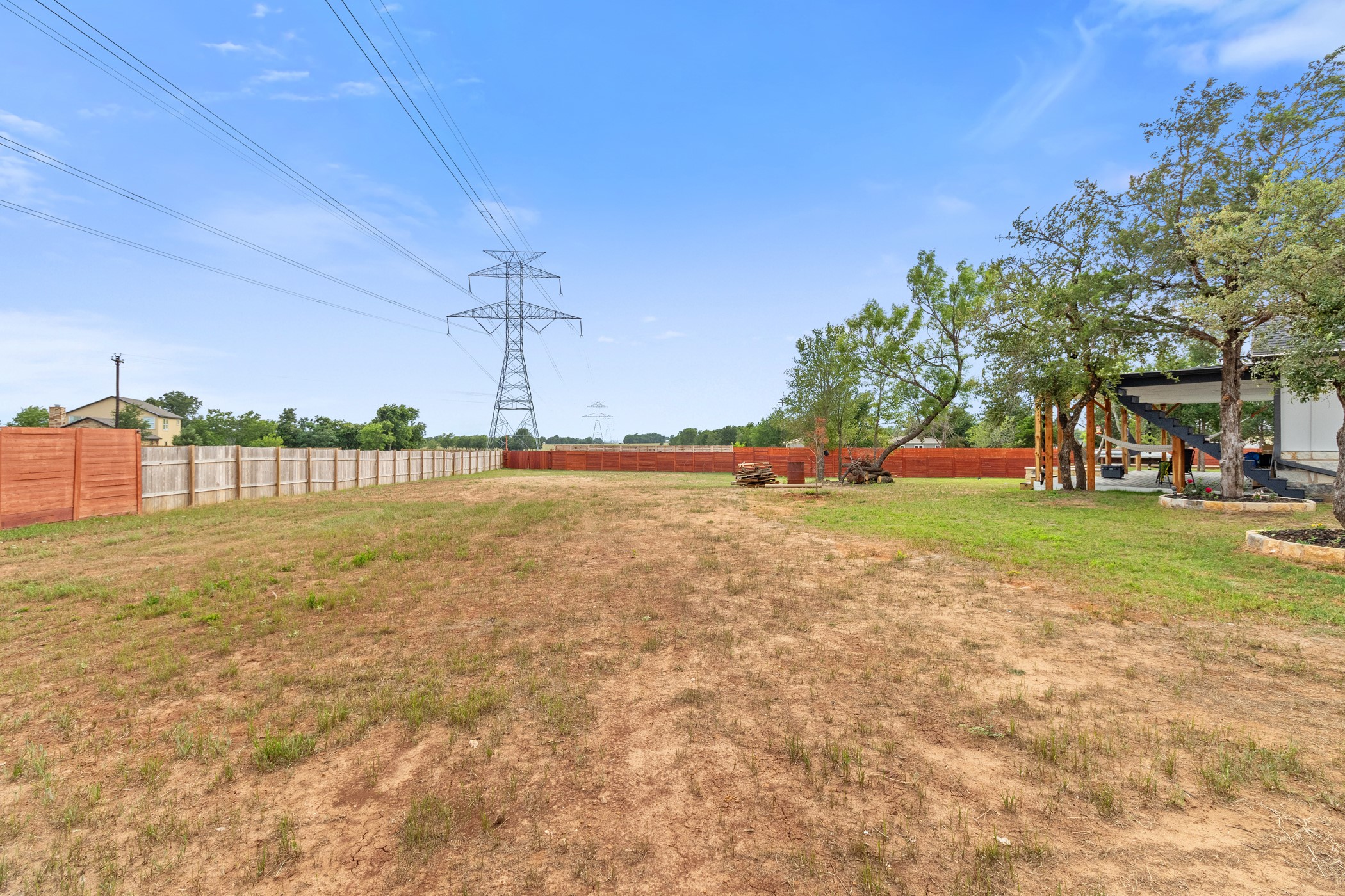 123 Zacate Street Elgin, TX 78621 - Photo 3 of 33 Expansive fenced yard featuring a mix of natural ground cover and grass, mature trees, and a covered patio structure