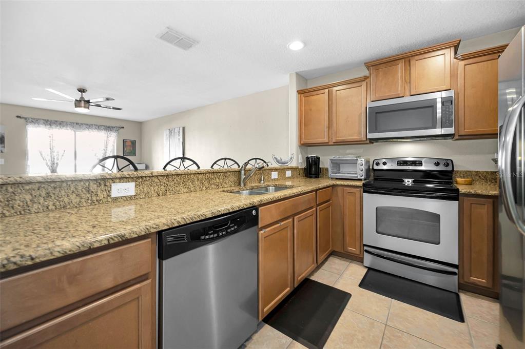 9736 Trumpet Vine Loop Trinity, FL 34655 - Photo 3 of 35 a kitchen with granite countertop a sink a stove and cabinets
