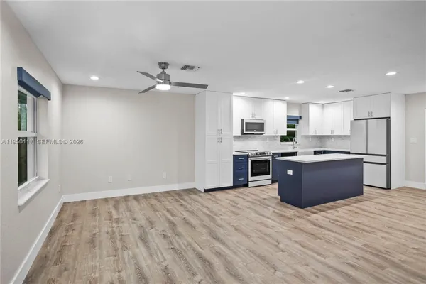a large kitchen with stainless steel appliances granite countertop a large counter top and white cabinets