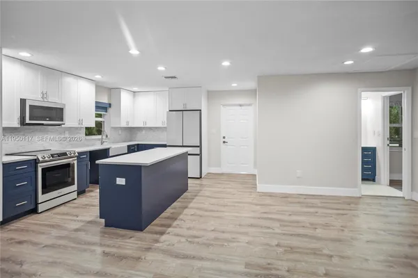 a large kitchen with stainless steel appliances granite countertop a stove a sink and a refrigerator