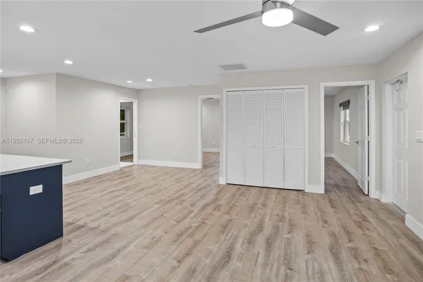 a view of an empty room with wooden floor and a ceiling fan