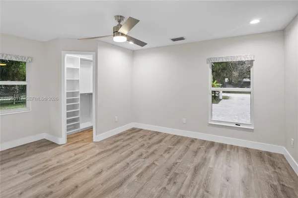 an empty room with wooden floor cabinet and windows