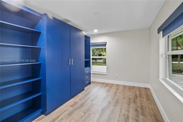 a view of empty room with wooden floor and fan