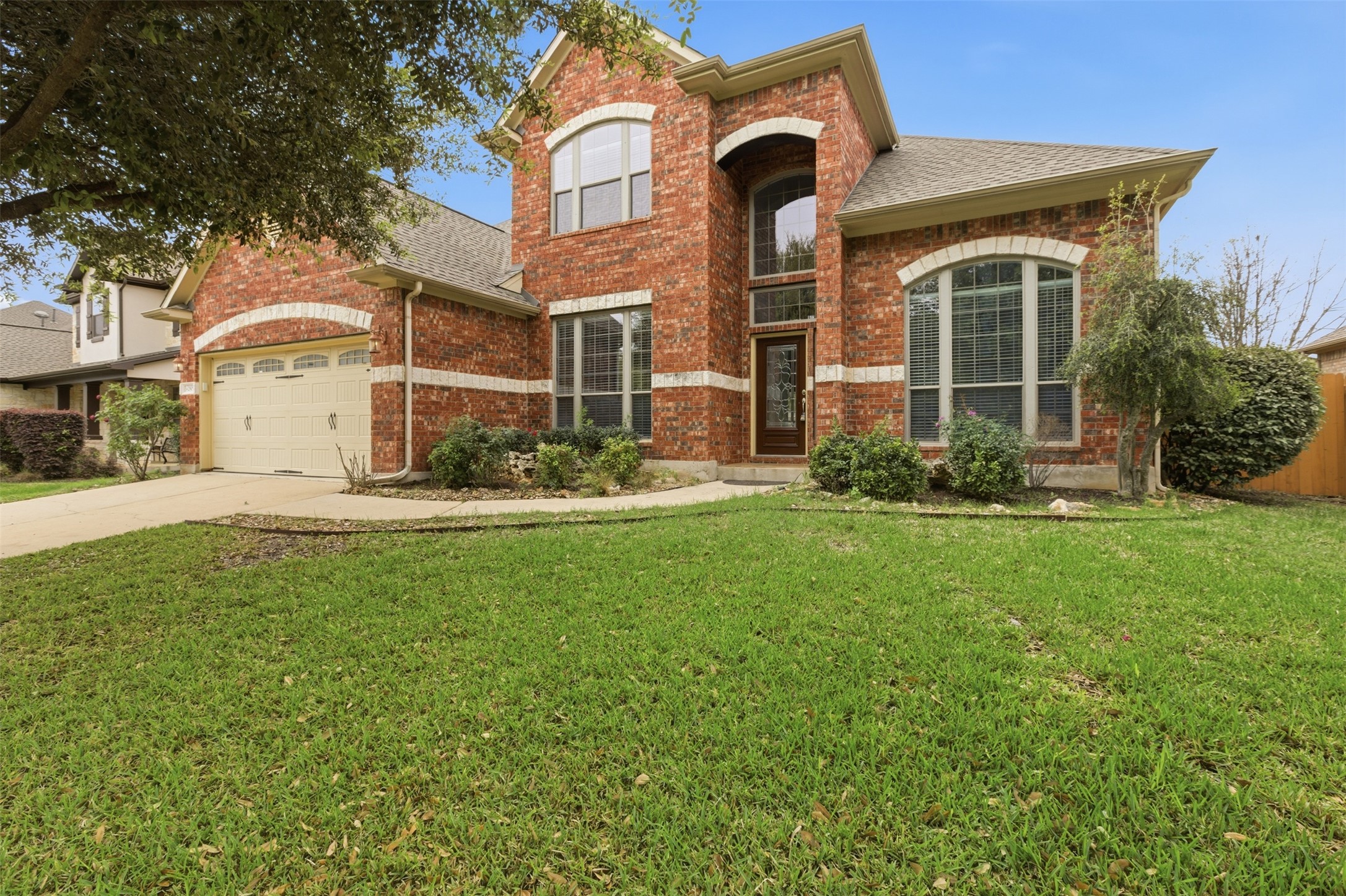 Traditional home featuring brick siding, a front yard, driveway, a 2.5 garage, and a shingled roof