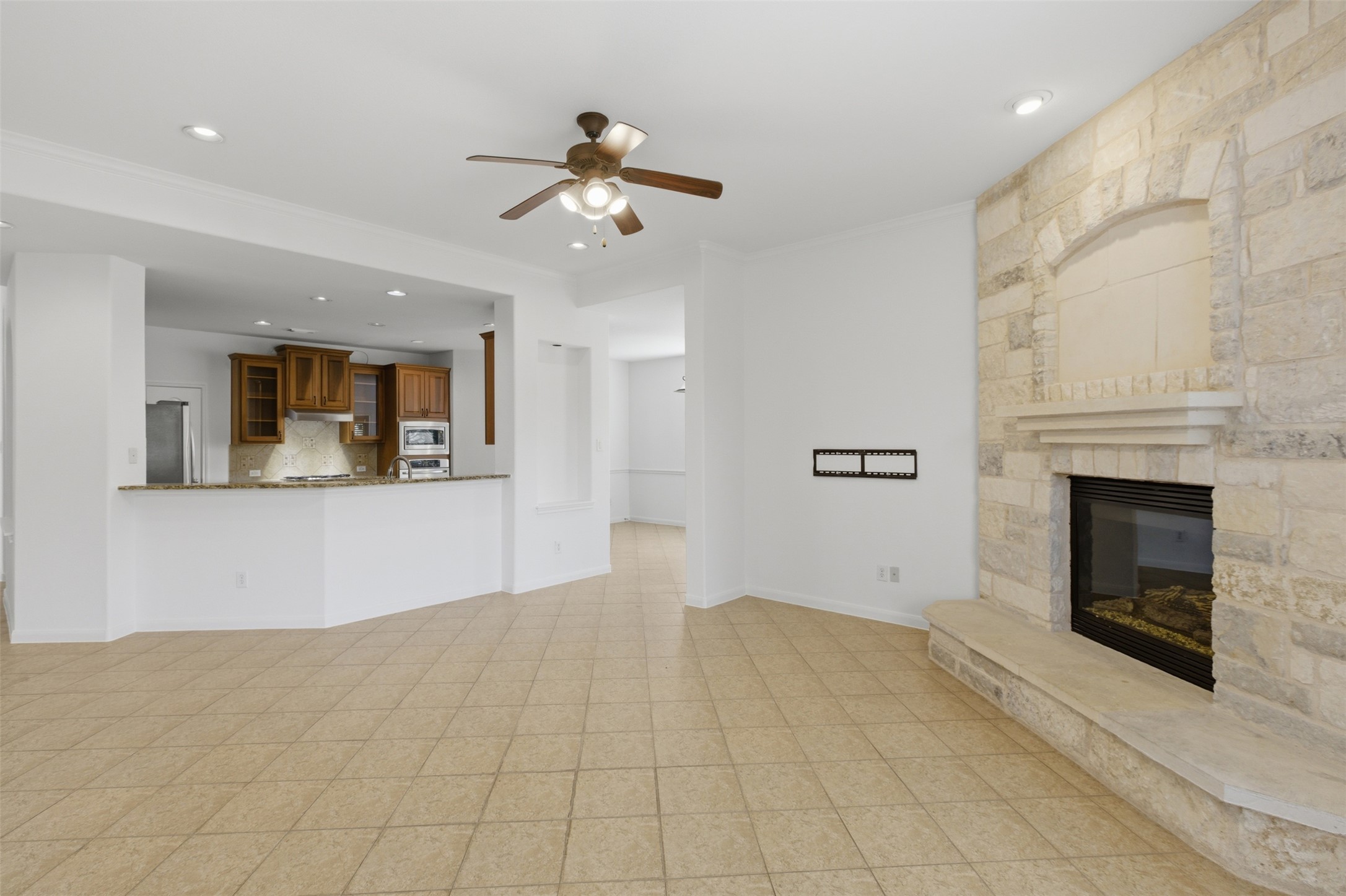 2909 Agave Loop Round Rock, TX 78681 - Photo 15 of 38 Family room featuring a ceiling fan, a stone fireplace, recessed lighting, and ornamental molding