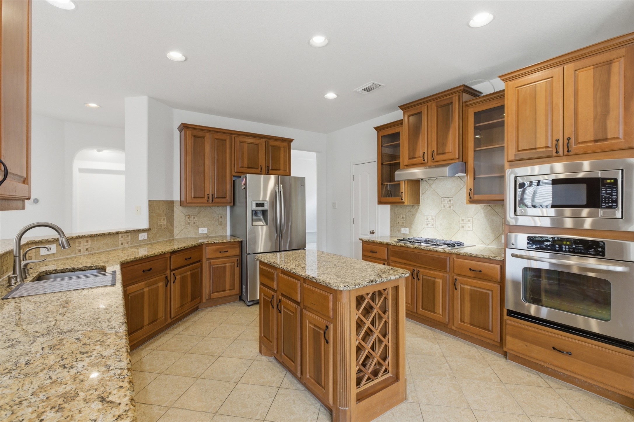2909 Agave Loop Round Rock, TX 78681 - Photo 9 of 38 Kitchen with wood finish cabinetry, light Granite stone counters, stainless steel appliances, glass fronted cabinets, and a kitchen island