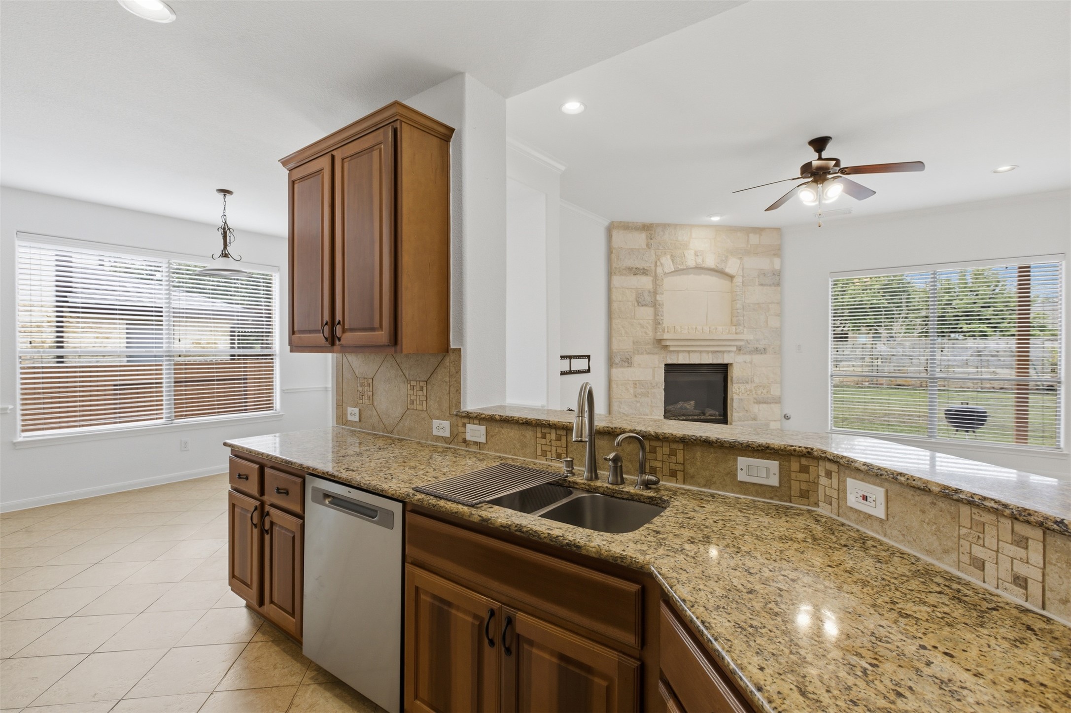 2909 Agave Loop Round Rock, TX 78681 - Photo 10 of 38 Kitchen featuring light Granite stone countertops, dishwasher, ceiling fan, decorative backsplash, and wood finish cabinetry